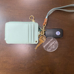 Clear keychain with the words "getaway car" written on it along with an image of a car. Attached to keys and a green wallet.