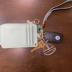 Clear sailboat keychain attached to keys and a green wallet