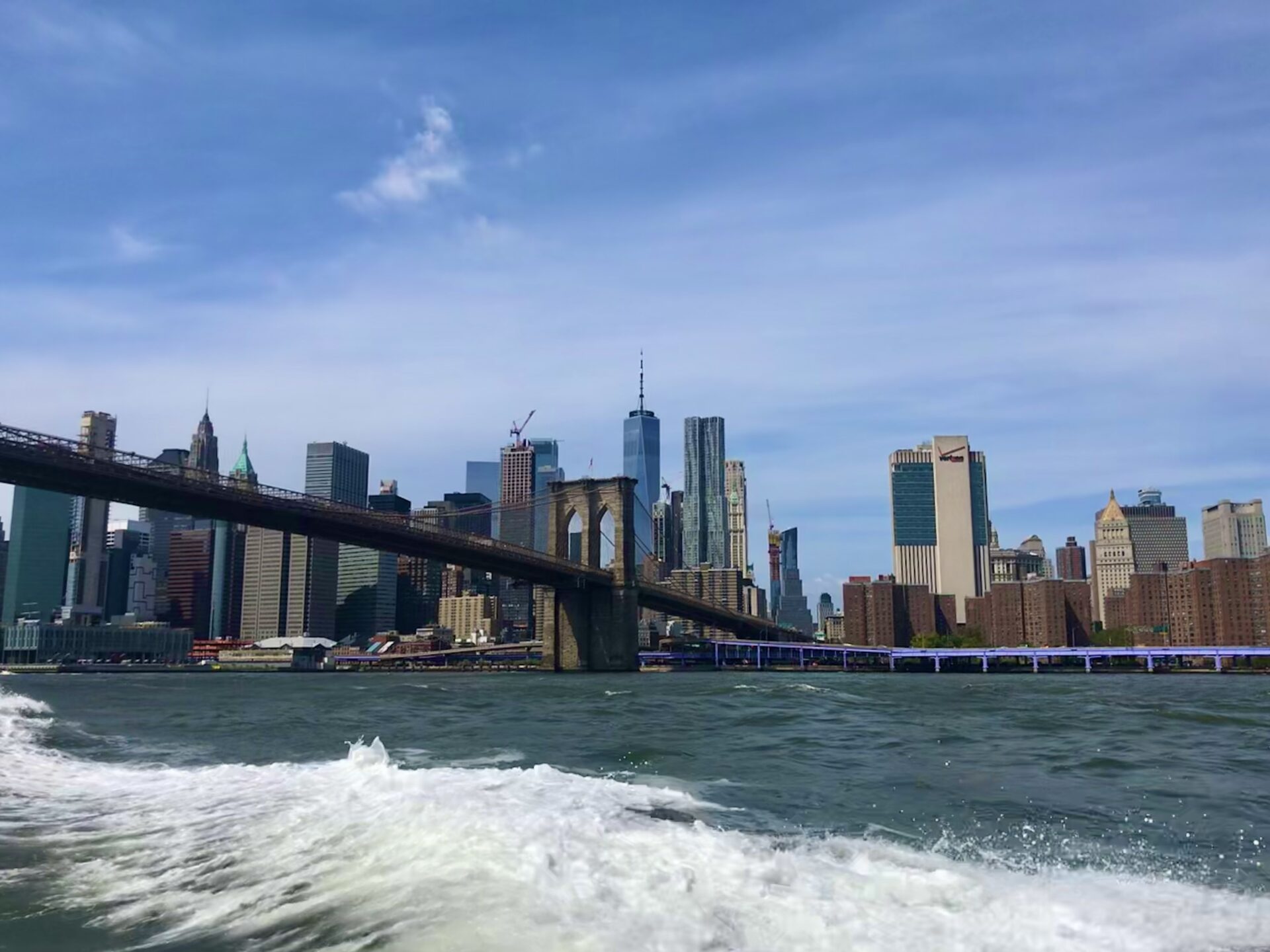 Photo of the Brooklyn Bridge in New York City taken from a boat on the water during the day.